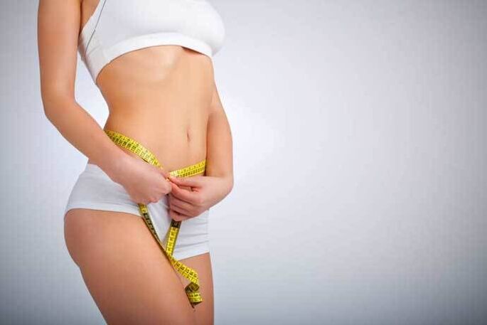 La fille mince mesure le volume de la taille